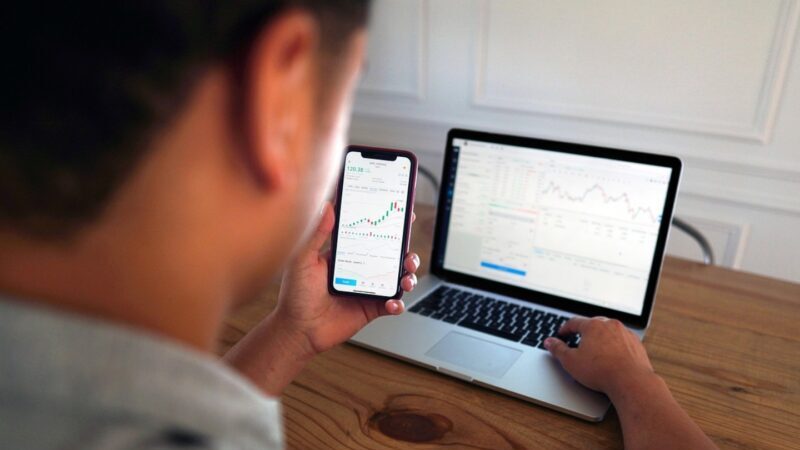 person looking at investment charts on screens